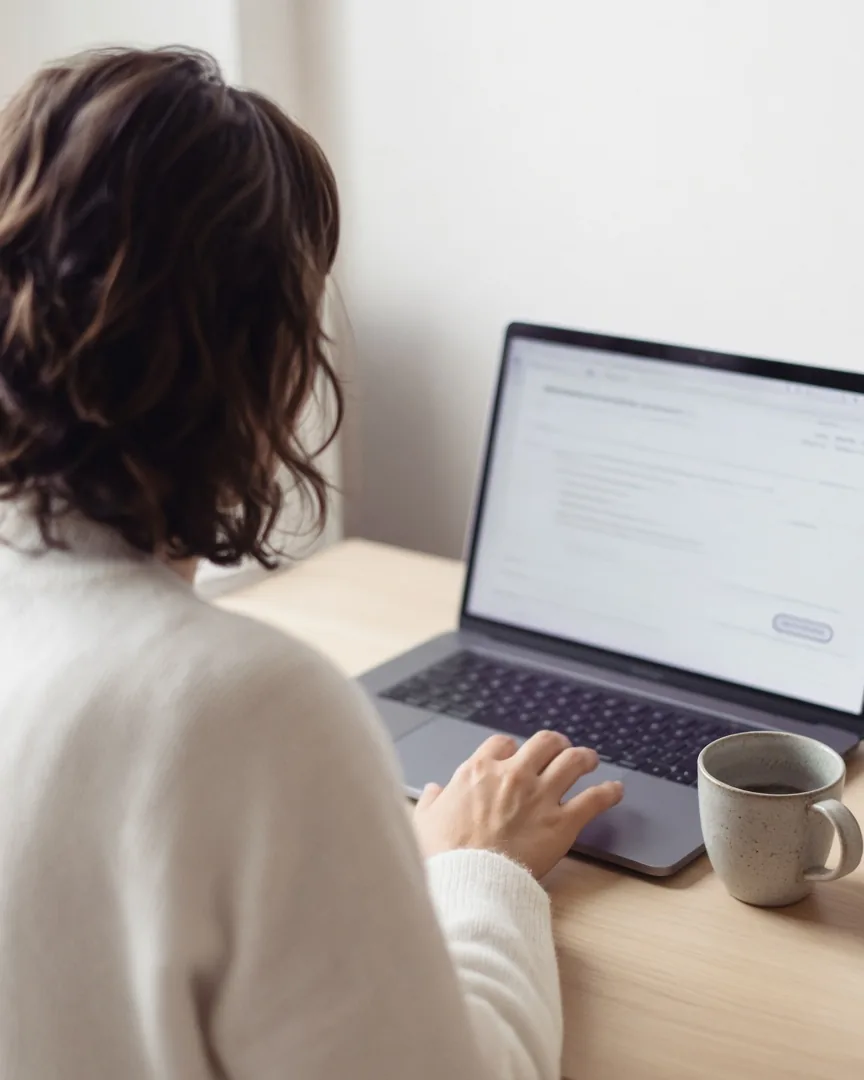 Vue par-dessus l’épaule d’une personne qui relit un e-mail sur son ordinateur portable, une tasse de café à côté.
